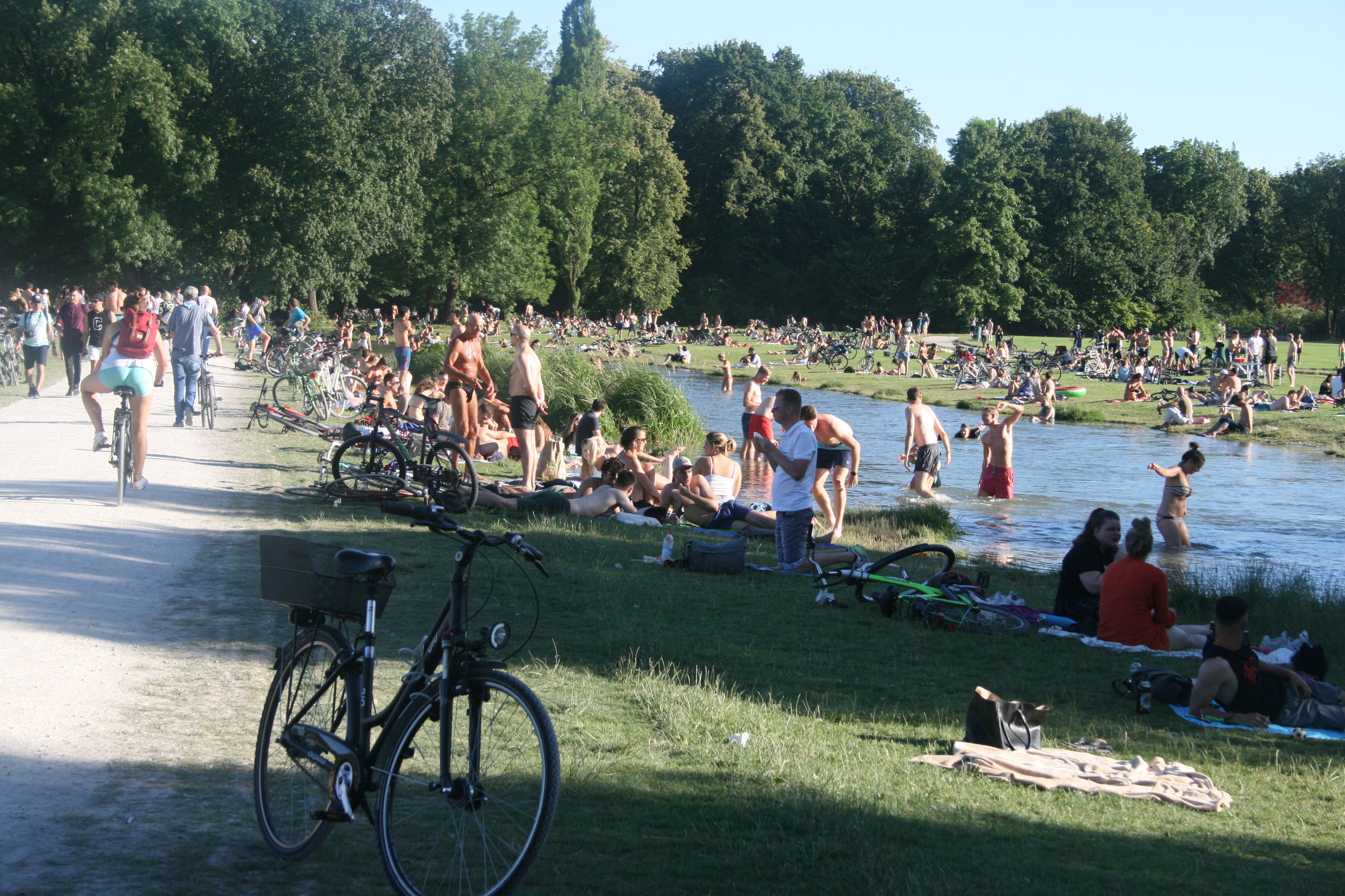 Teilnehmer der Radltour machen eine kurze Pause am Ufer der Isar in München.