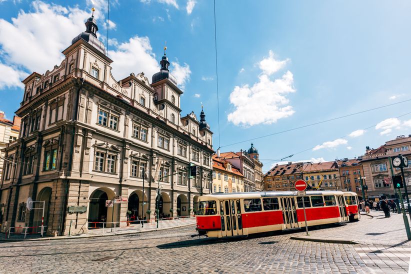 Rote Straßenbahn in Prag, fährt vor einer Kulisse aus historischen Gebäuden durch die Stadt.