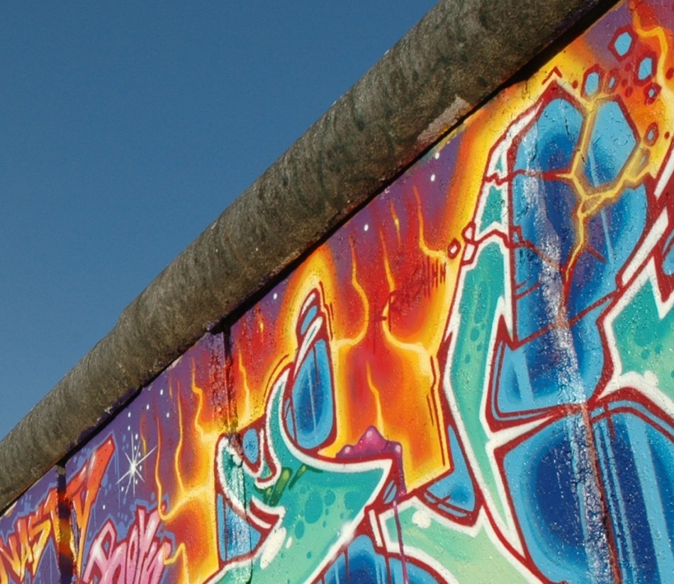 Bild des blauen Himmels, angeschnitten durch einen mit bunten Graffiti bemalten Abschnitt der Berliner Mauer - BAHNHIT.DE, © visitBerlin, Foto: Tanja Koch